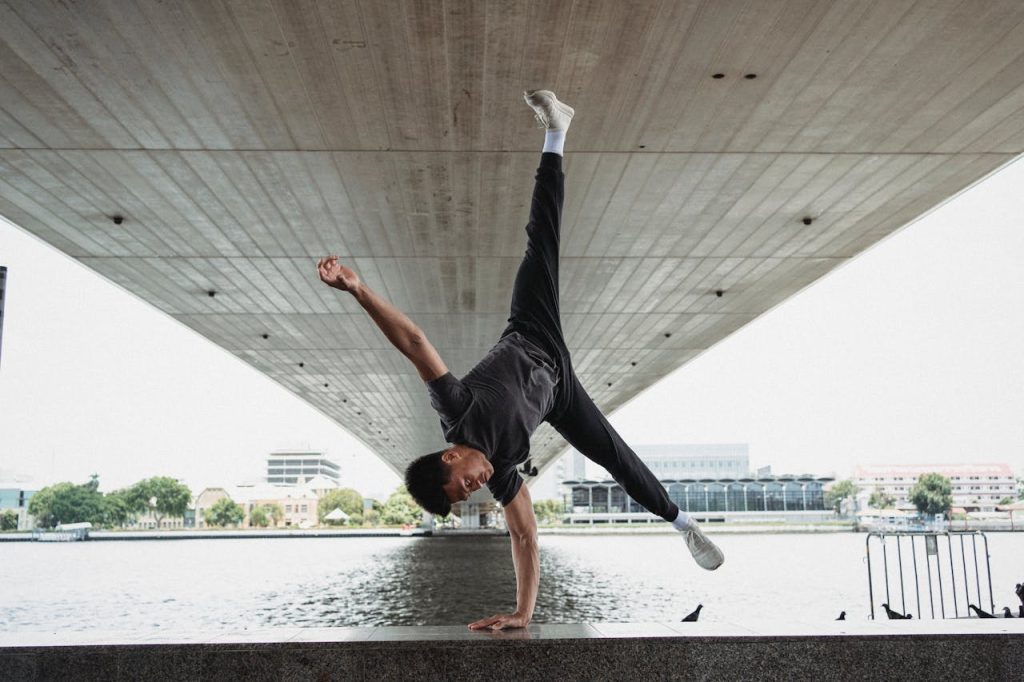 Young man doing handstand on fence of river embankment